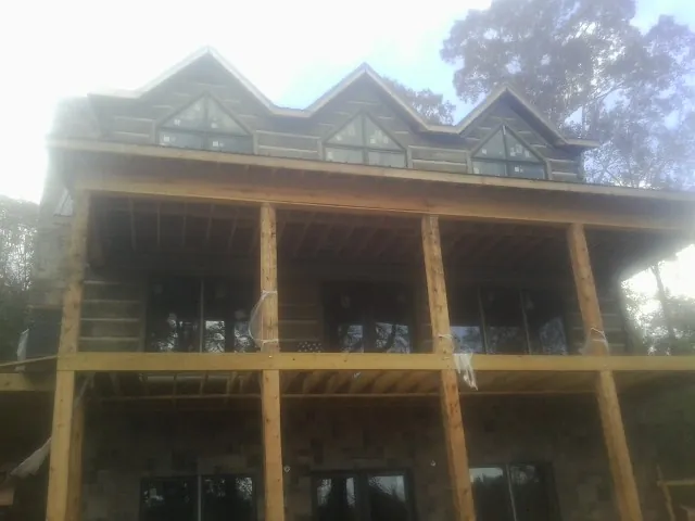 Dormers and porch framing on a large log home under construction — Roof Coating work by our crew in Hamlin