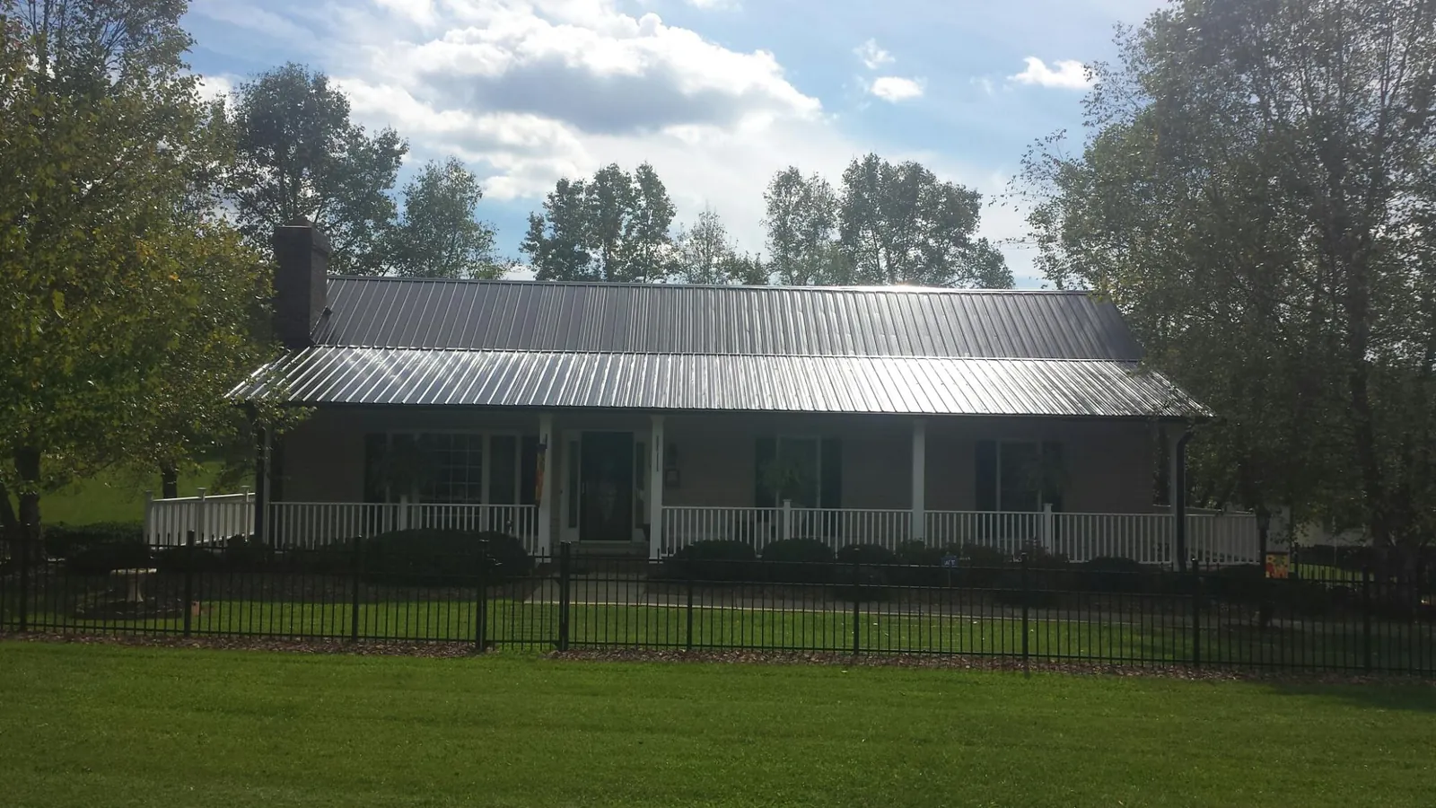 Gray metal roof on a brick ranch with a full width front porch — Gutter Guard Installation work by our crew in Hamlin