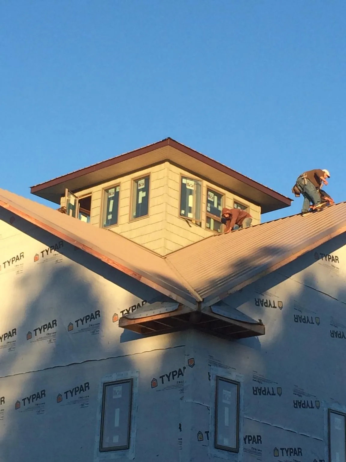 Roofers working around a rooftop cupola on a new metal roof at sunset — Roof Waterproofing in Hamlin by Roofing Brothers